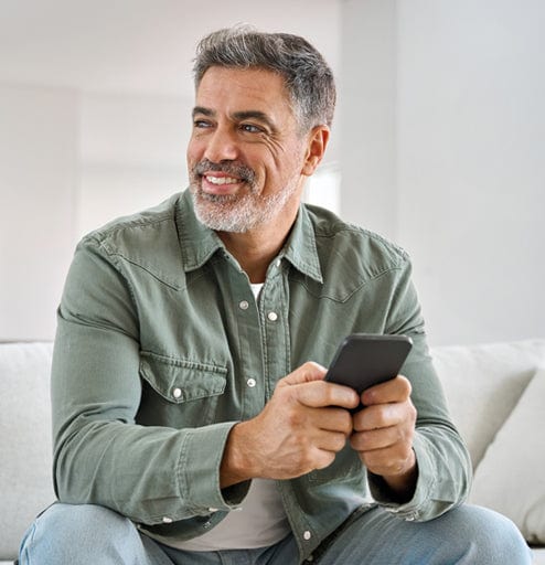 Middle-aged man using smartphone while relaxing at home