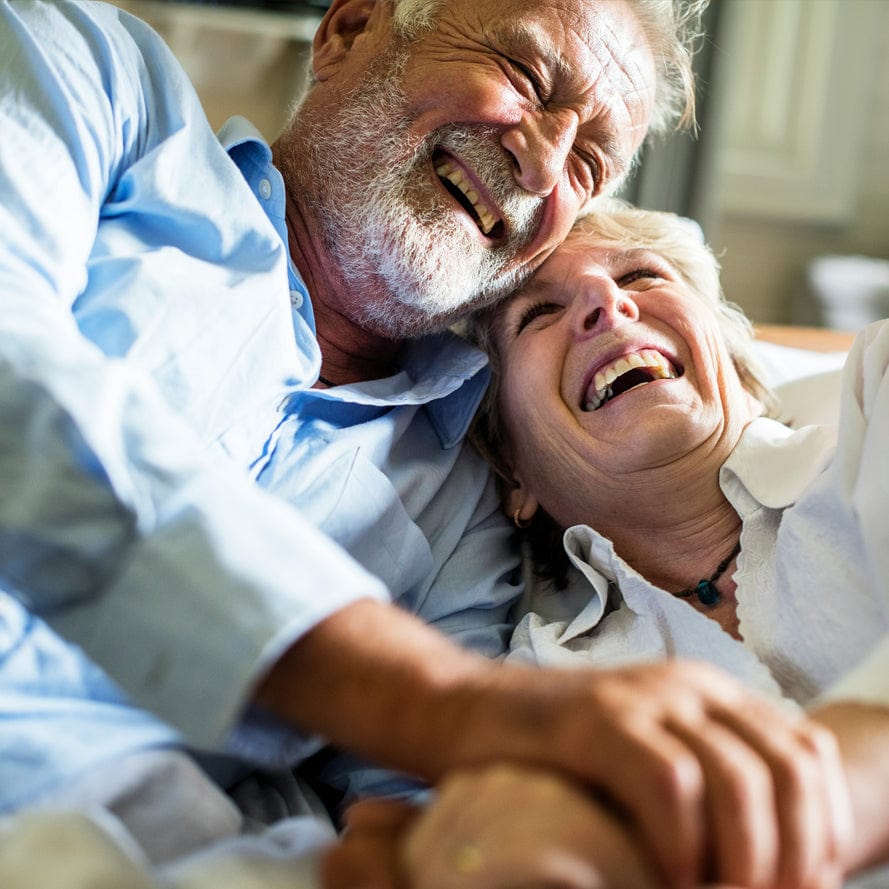 Older couple laughing together while watching television