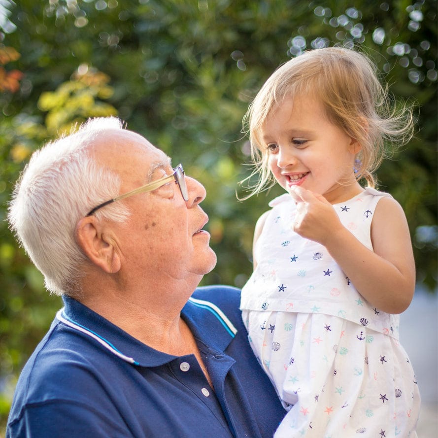 Older man smiling while talking with young child outdoors