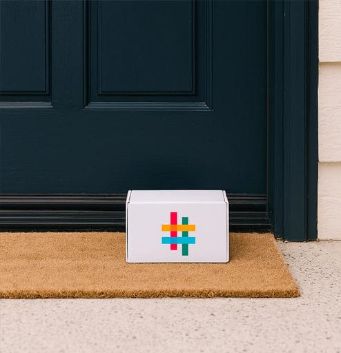 HearDirectClub delivery box placed on a front door doormat, representing home delivery of hearing aids and hearing care products